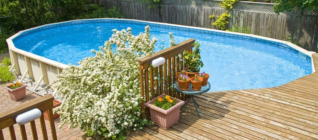 Newly installed pool with a deck and plants surrounding one side