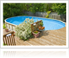 Swimming pool installed in backyard next to a deck and surrounded by plants